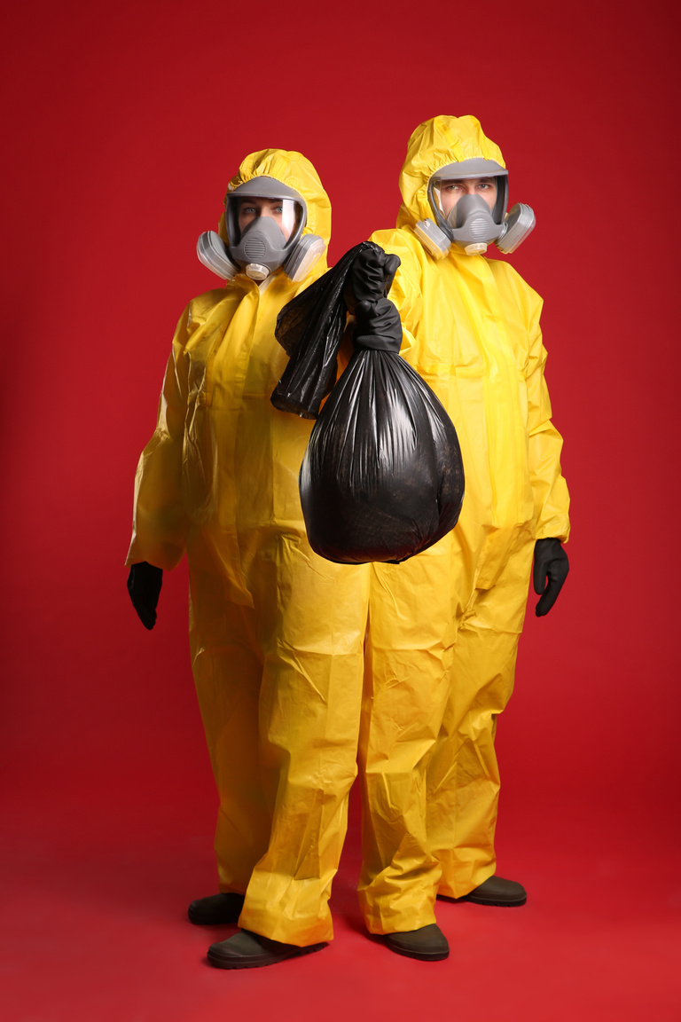 Man and Woman in Chemical Protective Suits Holding Trash Bag on